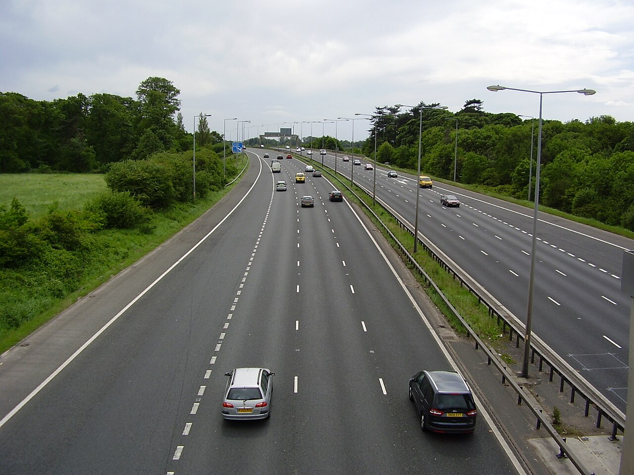 UK motorway with distance signs and cars at dusk