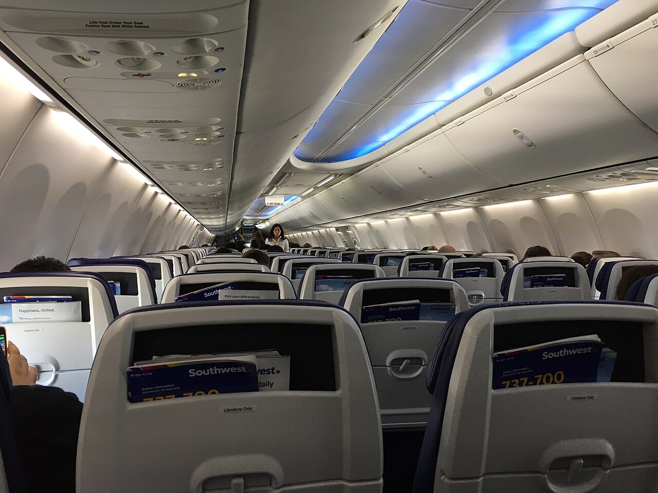 View down an airplane cabin aisle with rows of seats